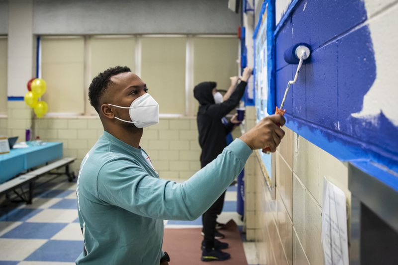 Mustapha Williams, 26, of Hyde Park, helps paint in the cafeteria as he and hundreds of other volunteers with City Year Chicago work to beautify Joseph Kellman Corporate Community Elementary School in East Garfield Park on Monday, Jan. 17, 2022.