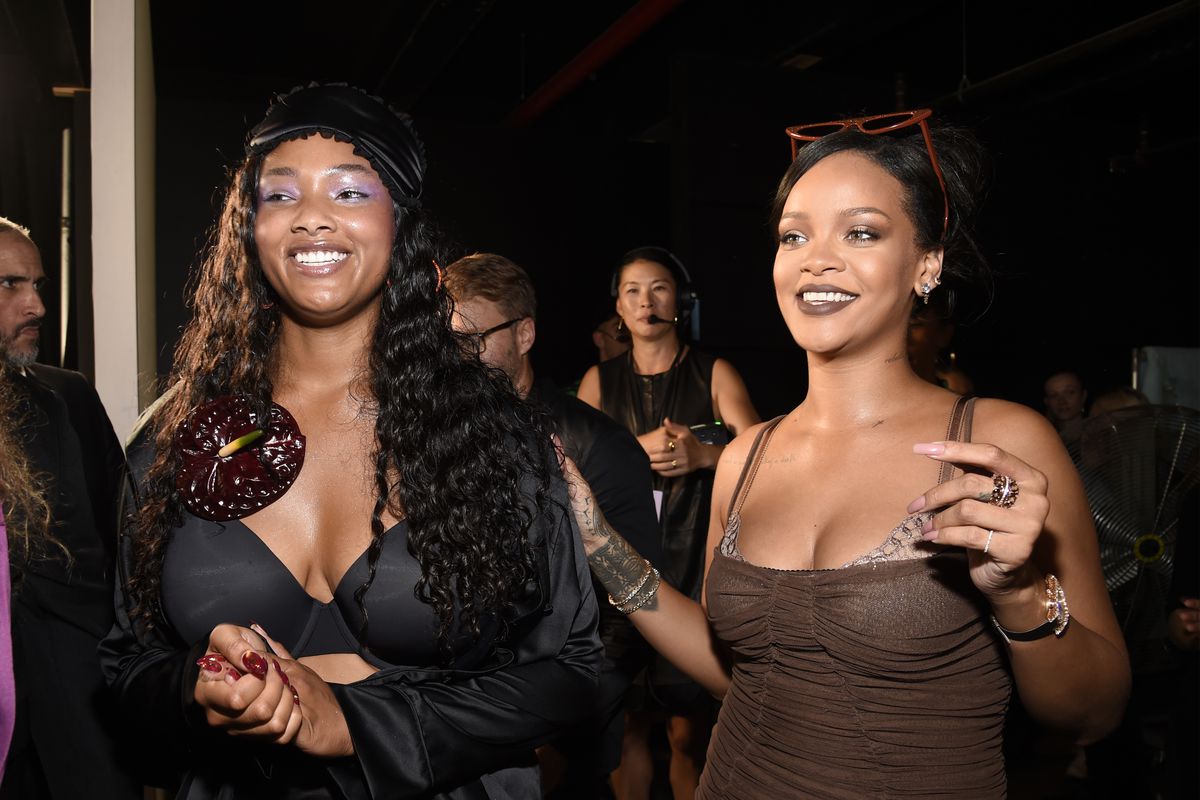 Rihanna and a model stand backstage, smiling.