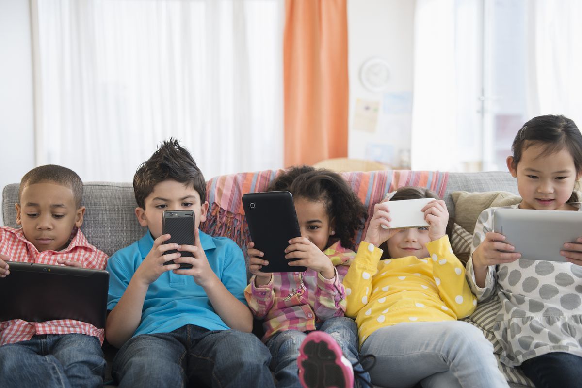 A bunch of kids watching videos on various handheld devices.