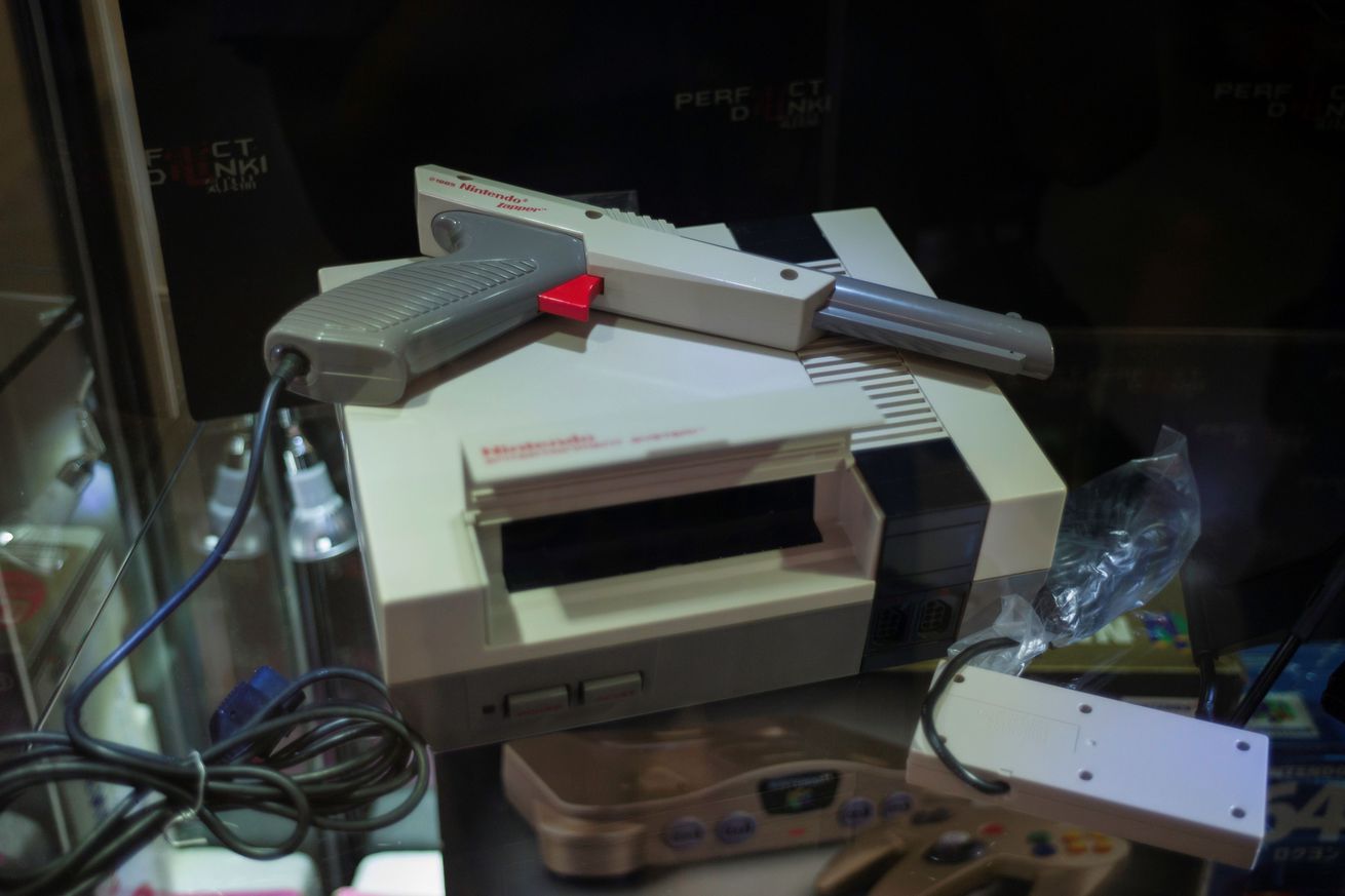 Photo of a Nintendo Entertainment System with a Zapper gun-like peripheral sitting on top with wires connecting the controller and the zapper bound besides the console