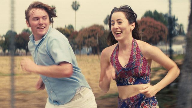 Gary and Alanna run alongside a field of dead grass in Licorice Pizza