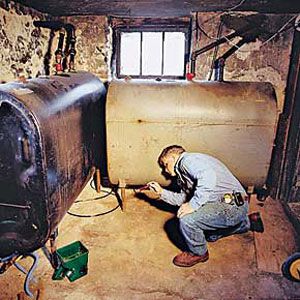 <p>Every basement has things that can leak, such as a furnace or water heater. Here, Tom checks the belly of an above-ground oil tank, looking for rust and drips.</p>