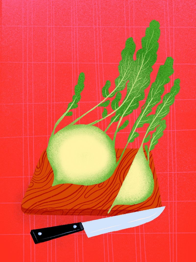 A whole kohlrabi sits on a wooden cutting board next to a large knife.