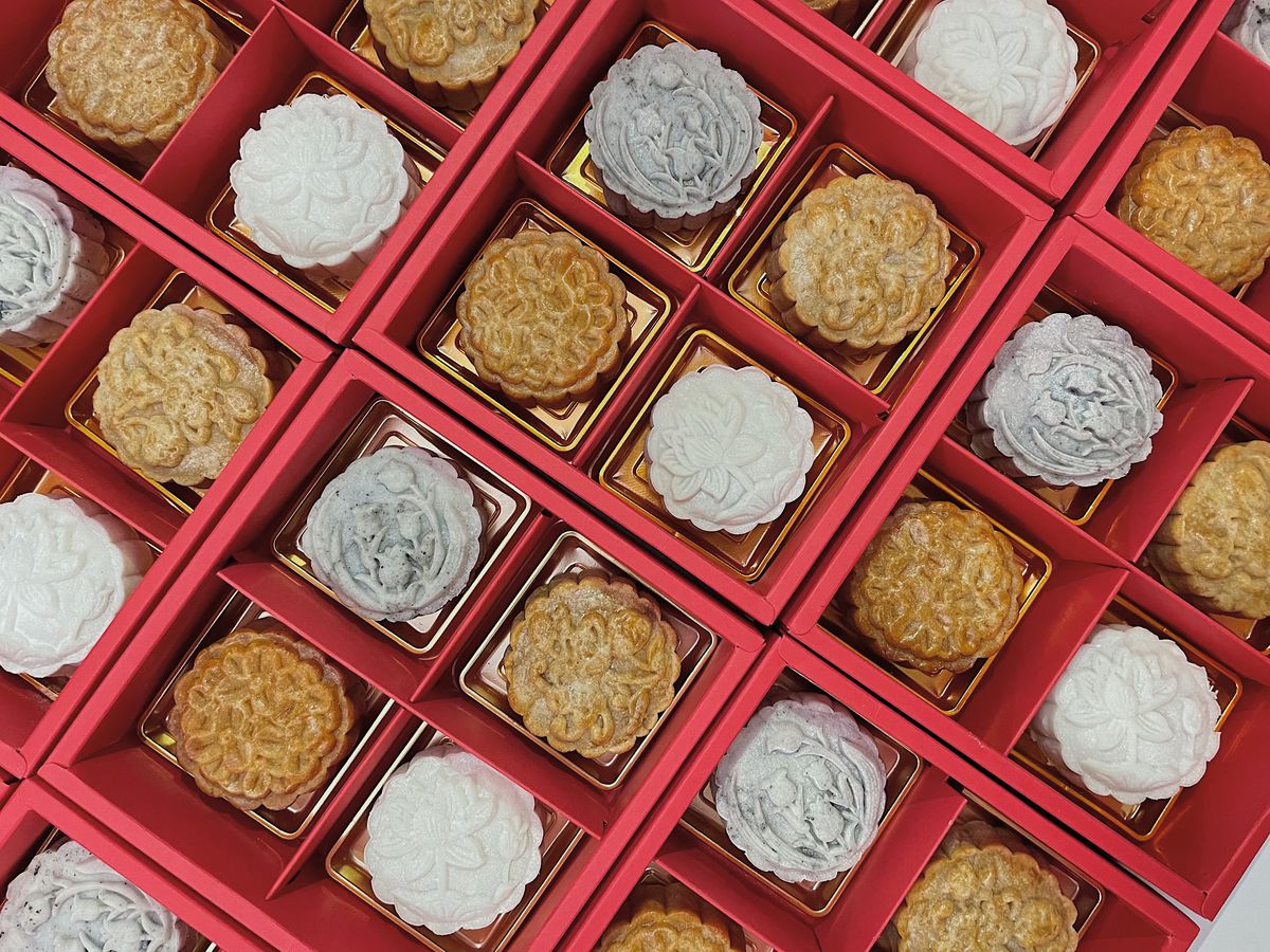 Rows of white, gray, and brown mooncakes with ornate patterns on them.