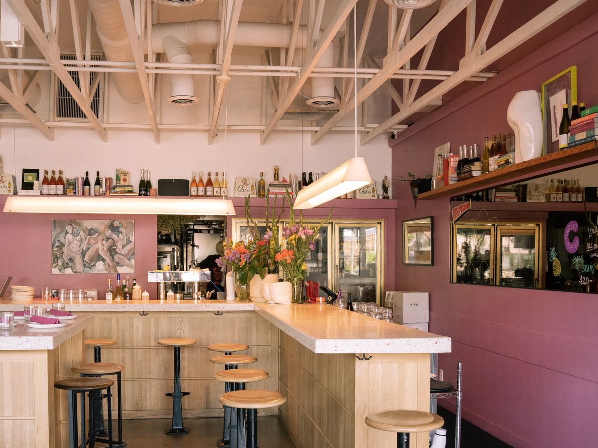 The interior of the Ruby Fruit, with pastel pink walls, light wood tones, and booty-themed decor.