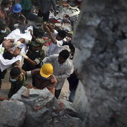 A survivor is evacuated from a garment factory building that collapsed Wednesday in Savar, near Dhaka, Bangladesh, Saturday, April 27, 2013. Police in Bangladesh took five people into custody in connection with the collapse of a shoddily-constructed building this week, as rescue workers pulled 19 survivors out of the rubble on Saturday and vowed to continue as long as necessary to find others despite fading hopes.
