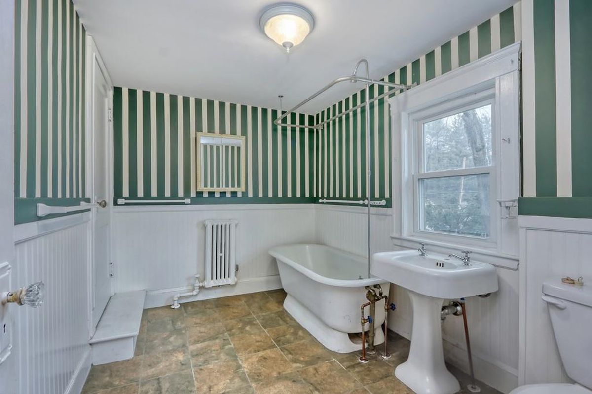 A bathroom with a step leading into it and a soaking tub next to the sink, and the wallpaper design is pretty striking.