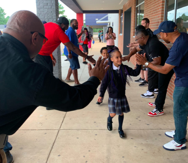 Community members in the Hickory Hill neighborhood offer cheers and high-fives to welcome students back to Power Center Academy Elementary School.