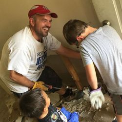 Deseret News sports writer Jody Genessy smiles while being helped by two young Texans while removing soggy sheetrock from a house that sustained flood damage after Hurricane Harvey.