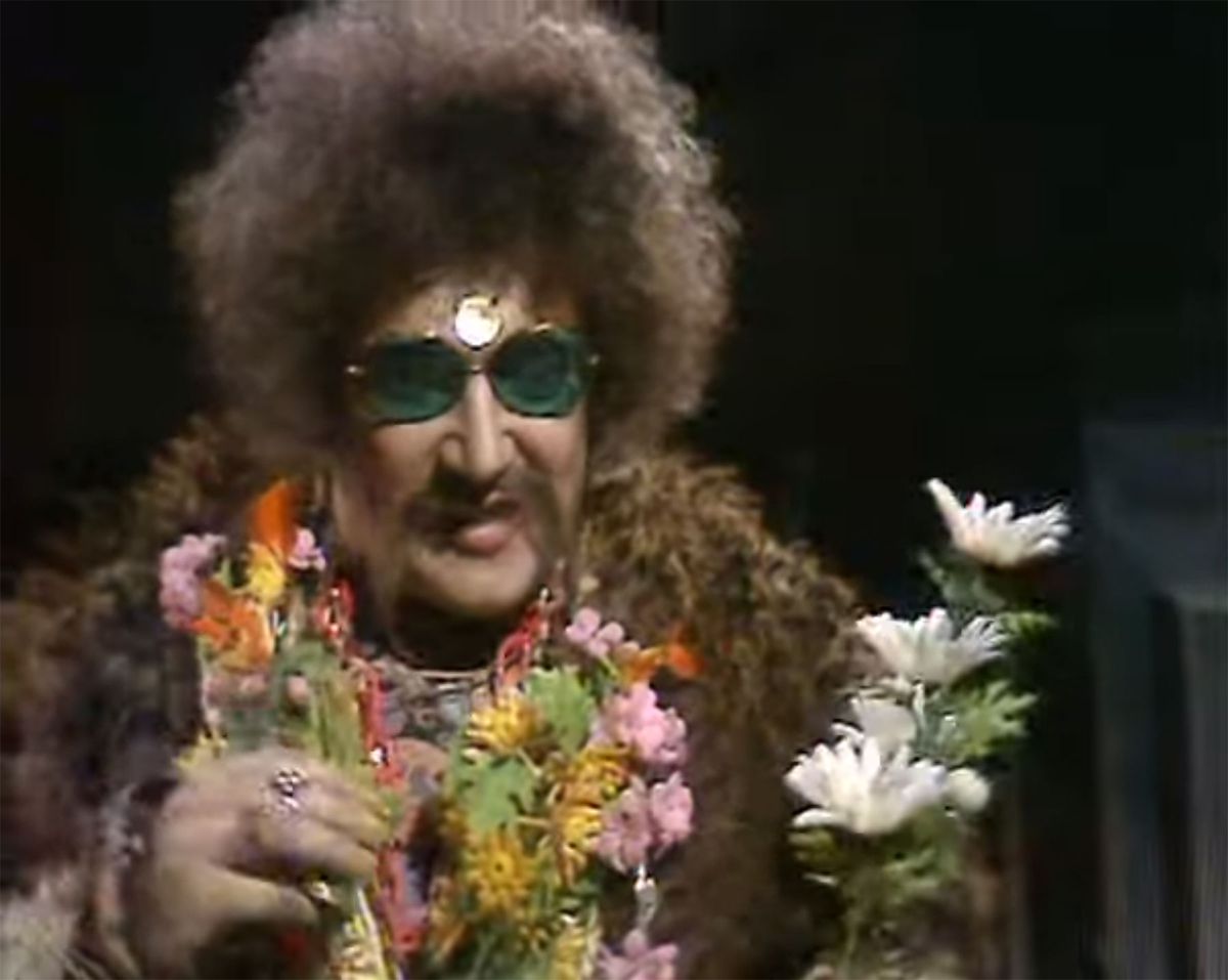 A stereotypical afro sunglasses hippie wears a necklace of flowers in a black void