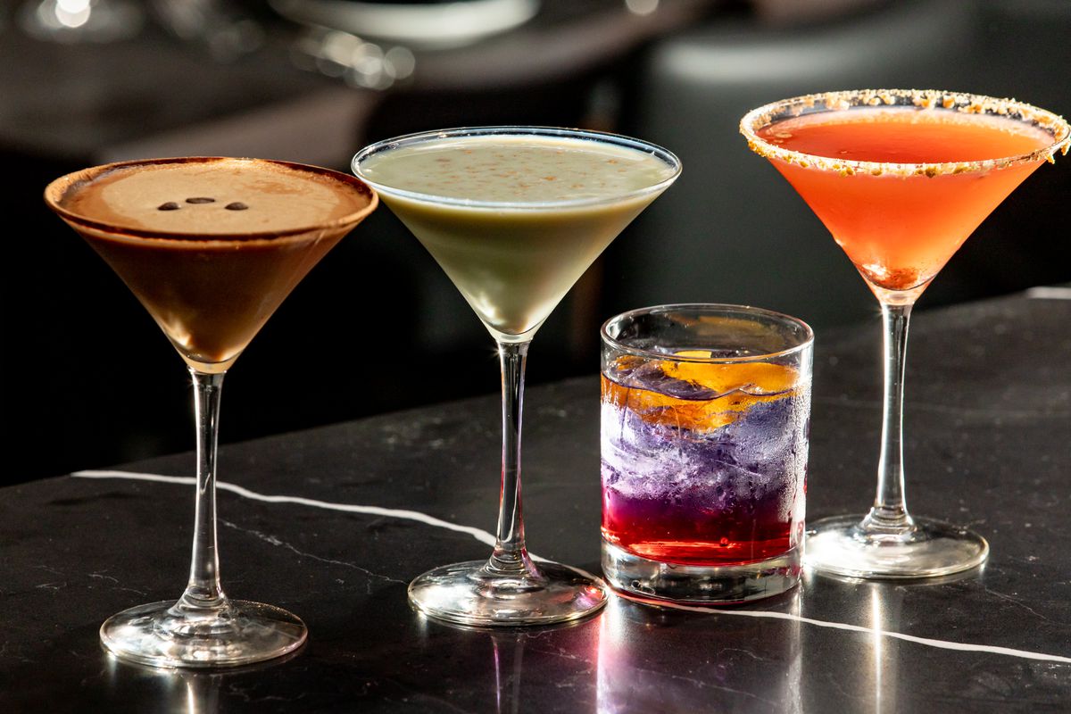 Four unique cocktails are lined up next to each other on a bar table. 