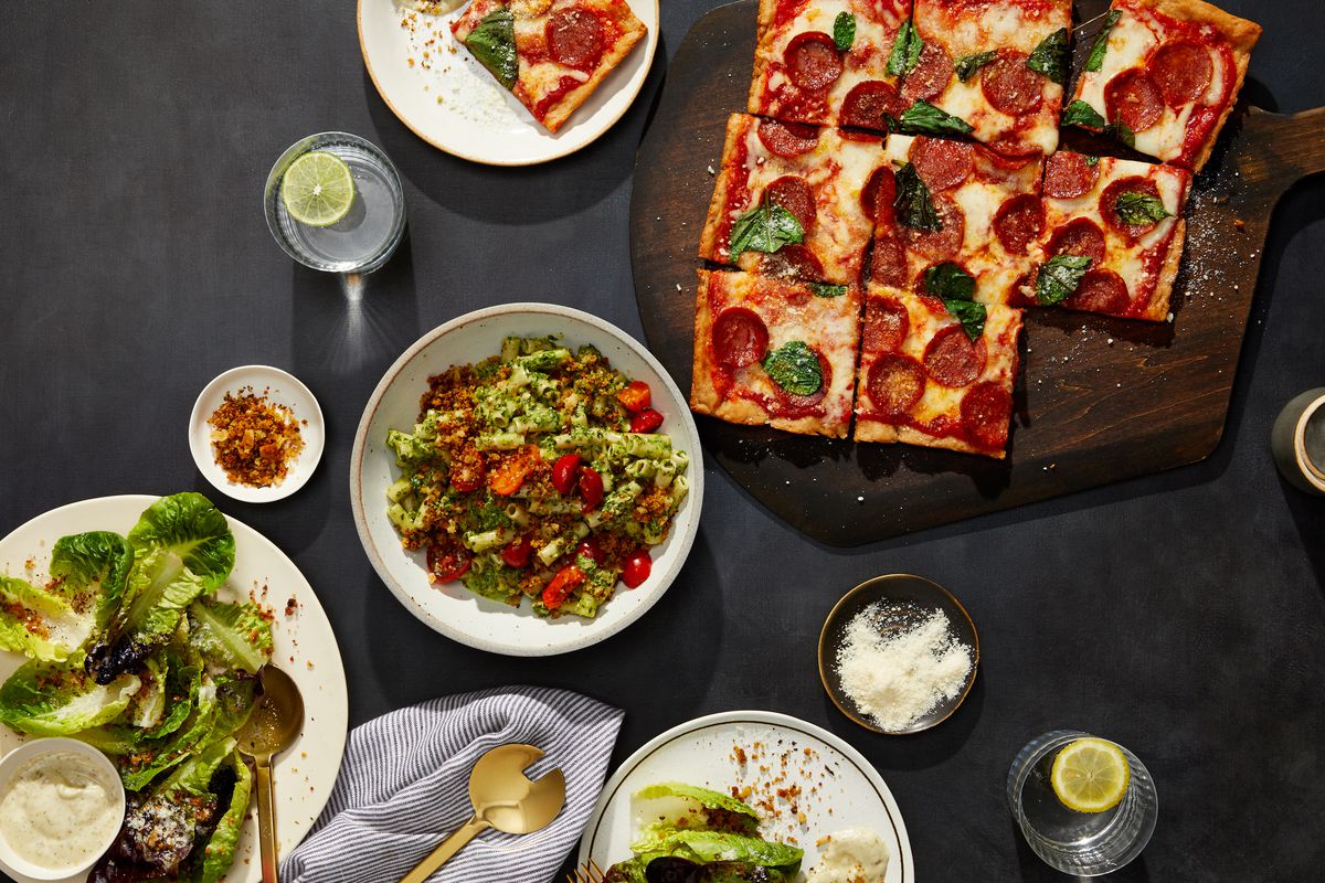 A square pepperoni pizza, assortment of salads, and pesto pasta.