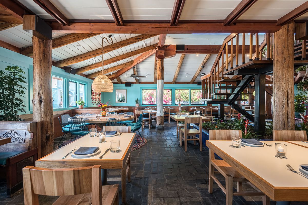 A teal restaurant interior at daytime with wooden beams and white paint touches.