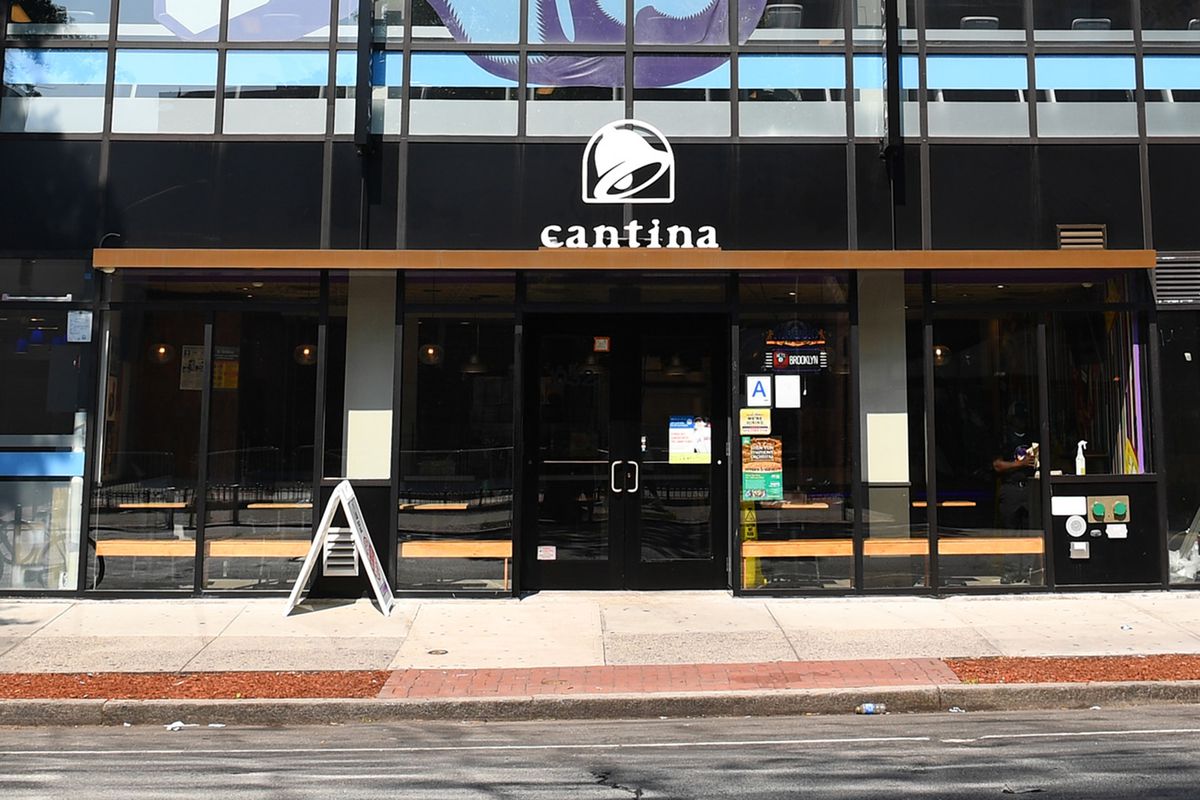 A storefront with a sign propped on its sidewalk with the Taco Bell logo and a sign that reads “cantina”