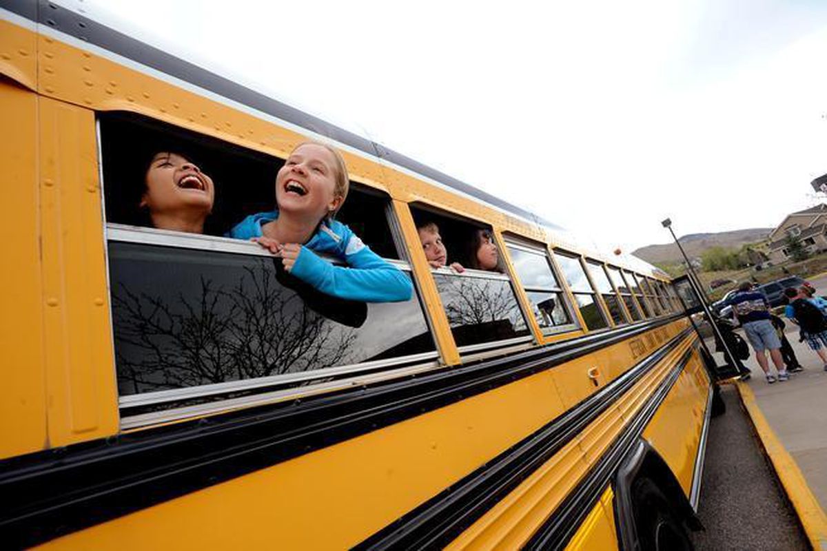 Fourth-graders Kintan Surghani, left, and Rachel Anderson laugh out the school bus window at Mitchell Elementary School in Golden.