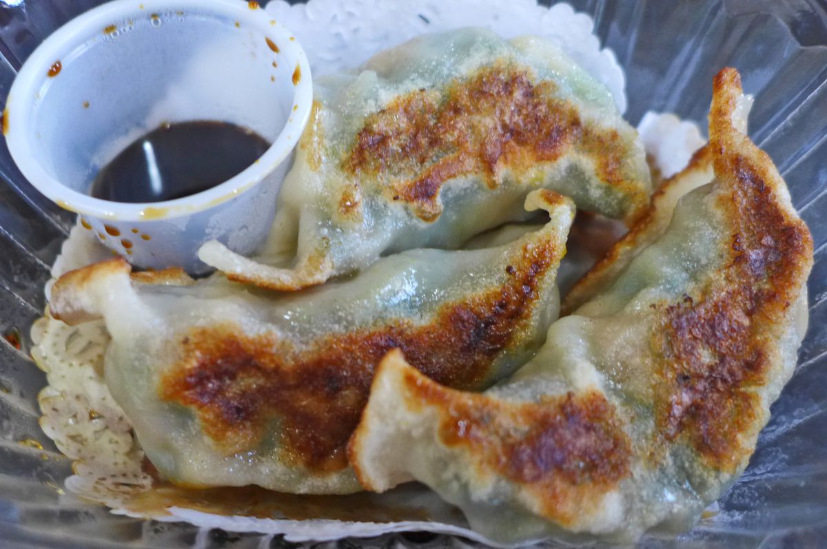 Three horn shaped dumplings and small cup of dark dipping sauce.