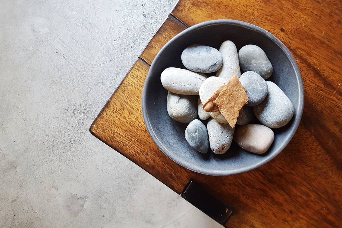 A small bite from a tasting menu restaurant, served on a bowl of rocks.
