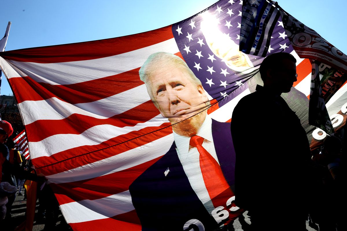 An image of Trump against the backdrop of an American flag with sun shining through it. 