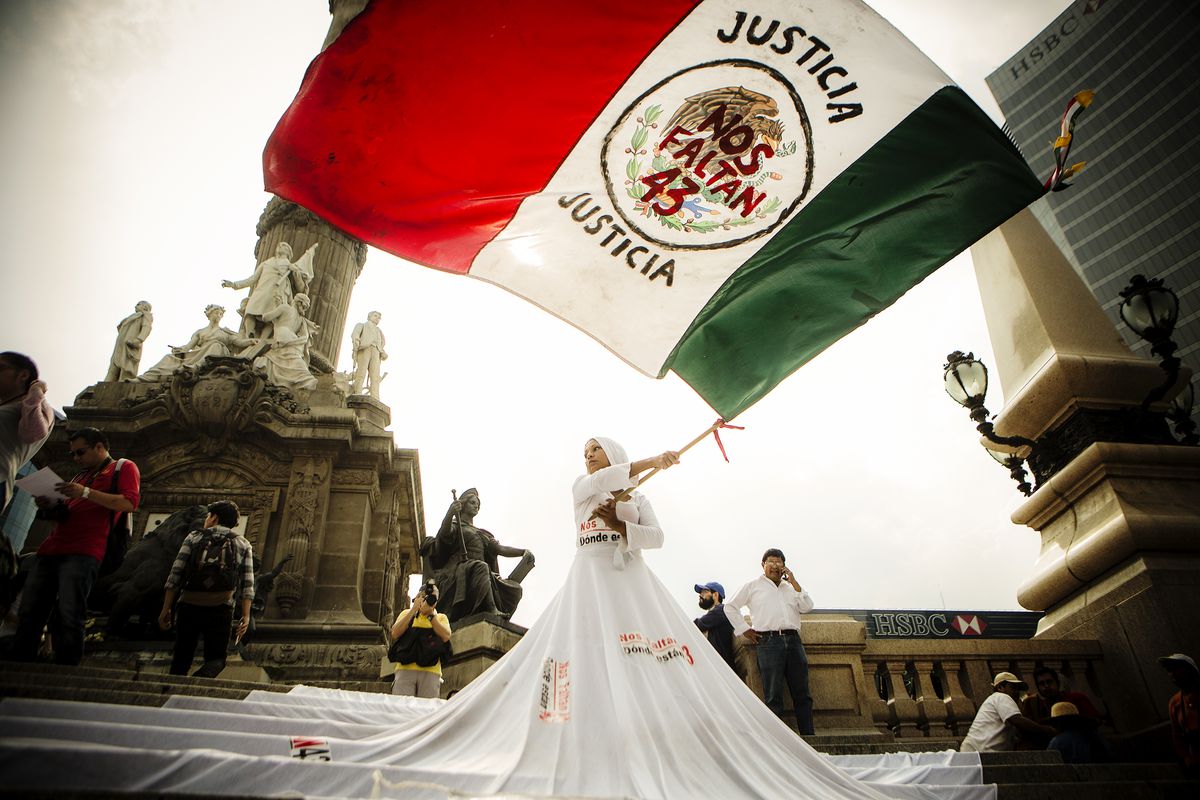 A woman waves a flag during the silent protest to mark 3 years of the disappearance of the students of Ayotzinapa. Mexico City, Mexico. September 26, 2017.