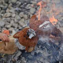 A teddybear burns on a fire outside a tent at the northern Greek border station of Idomeni, Friday, March 11, 2016.  After nearly three days of rain, conditions in the refugee camp on the Greek-Macedonian where about 14,000 people are stranded have deteriorated significantly, with many of its residents struggling to re-pitch their small camping tents in slightly drier patches.