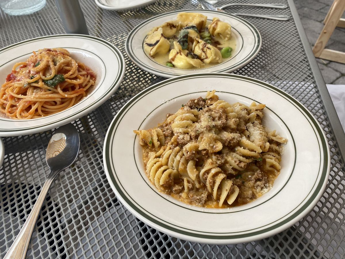Three pasta dishes blanketed in red and white sauces are arranged on a plate.