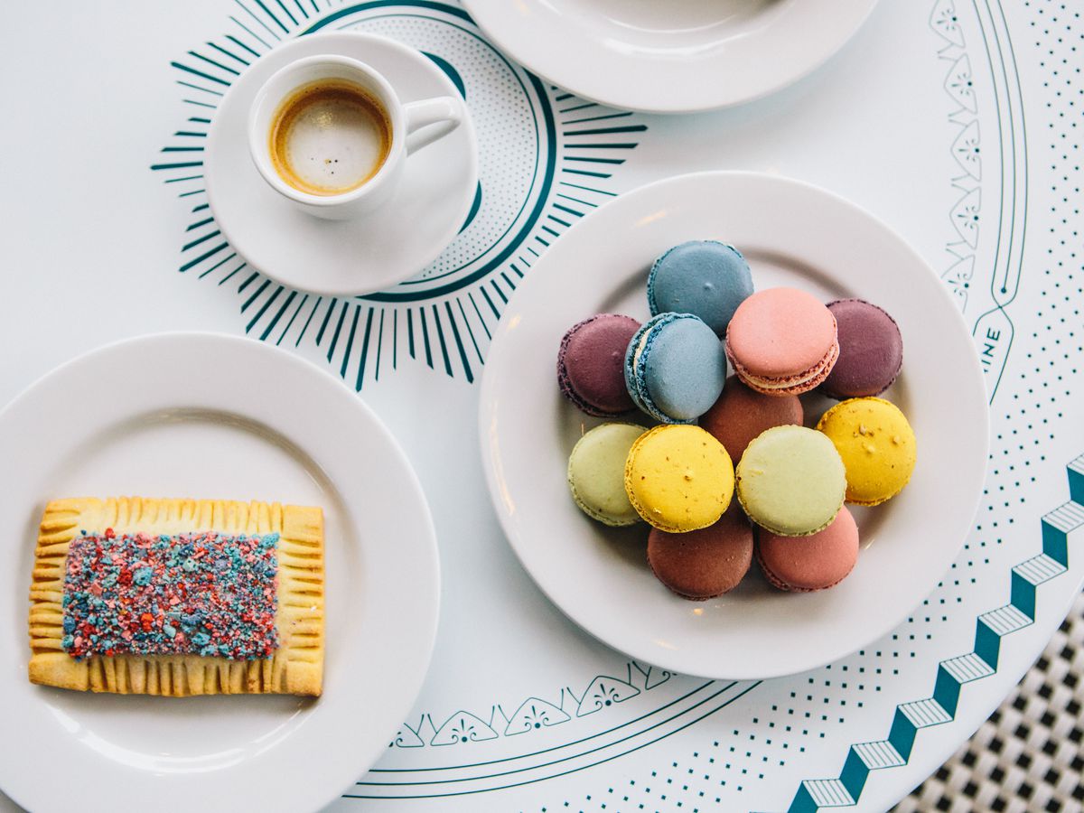 A plate of pastel-colored macarons and another plate of a sprinkle-laden pop tart.
