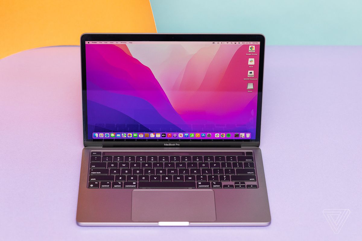 Apple MacBook Pro 13 2022, lavanta rengi bir arka plan üzerinde yukarıdan görülüyor.