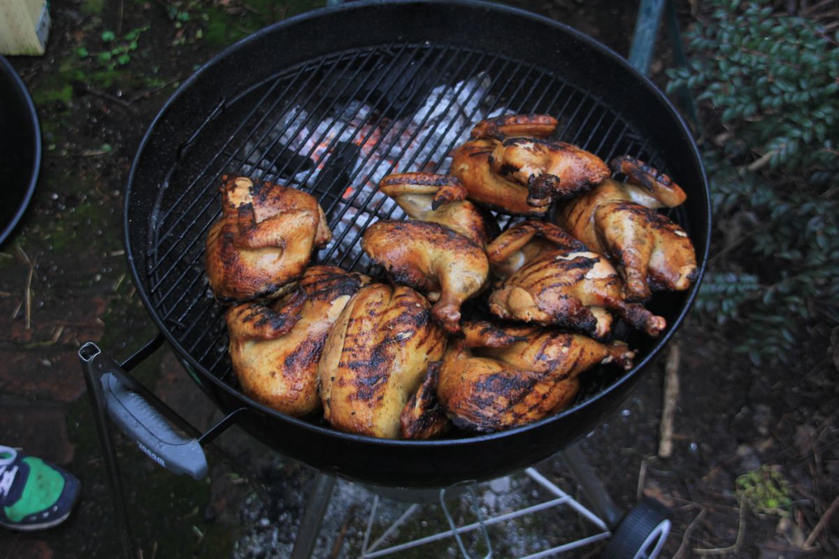 A grill is crowded with chicken legs and breasts with grill marks