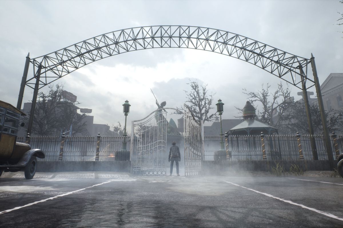 A man stands under a spooky iron gate.