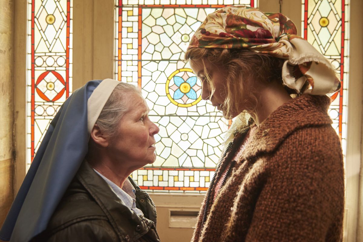 Imelda Staunton and Carla Juri face off in front of a stained-glass window in the horror movie Amulet.