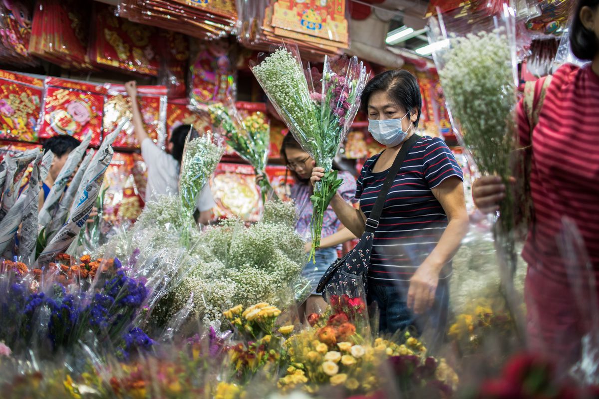 An old woman wears a surgical mask while buying flowers...