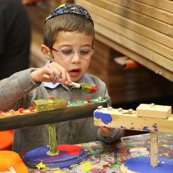 Shneor Steiger paints his Menorah as three Jewish communities come together at the Home Depot for a menorah-building workshop in Salt Lake City on Sunday, Dec. 18, 2016.