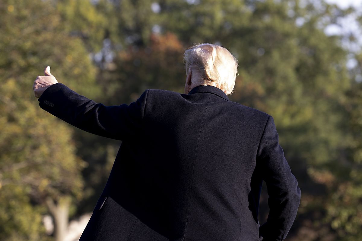 President Donald Trump, seen from the back, gives a thumbs-up gesture.