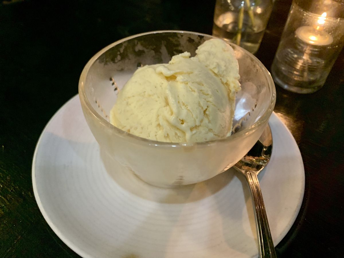 A scoop of off-white ice cream in a glass bowl
