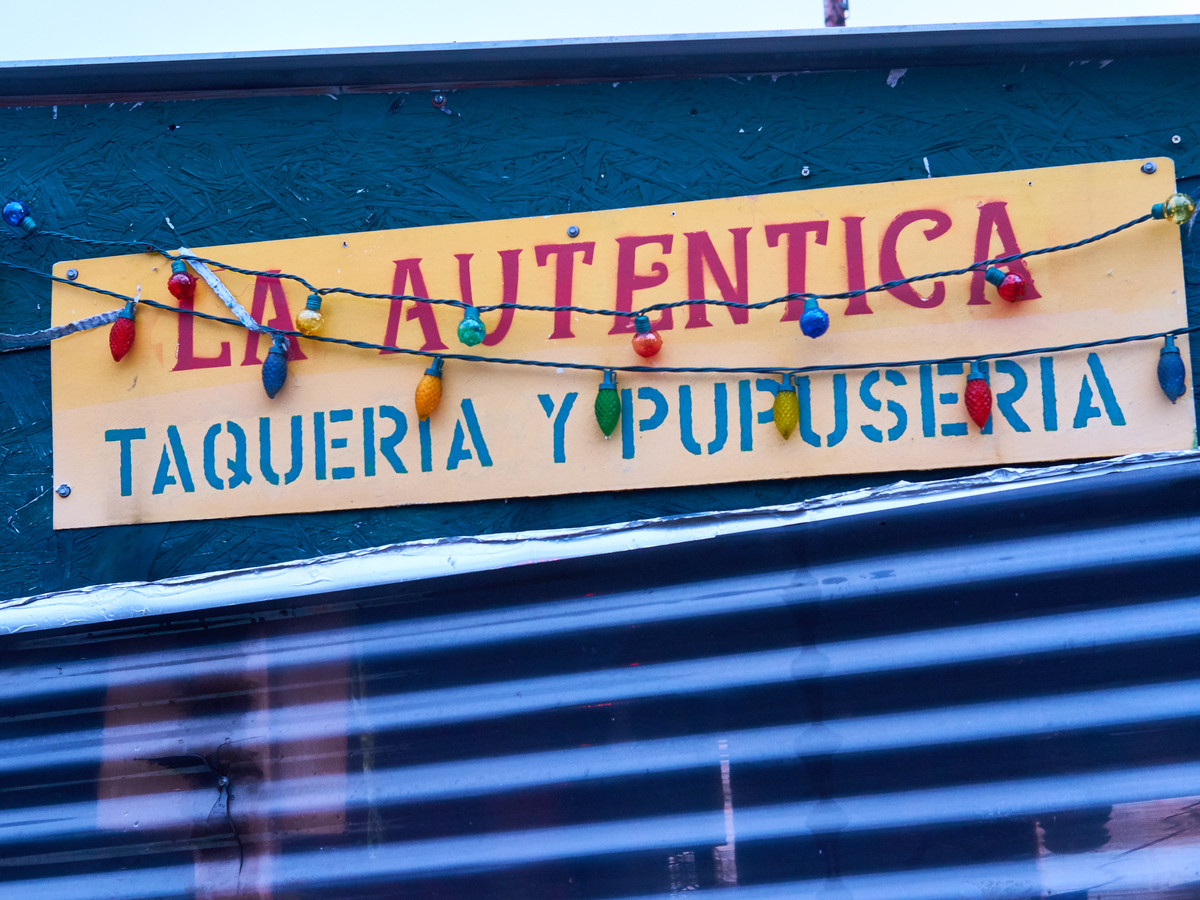 A hand-painted sign for La Autentica covered in colored lights
