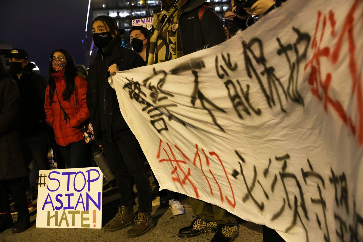 Activists in Chinatown in Washington, DC, hold up a banner written in Chinese and a sign that reads “Stop Asian hate.”