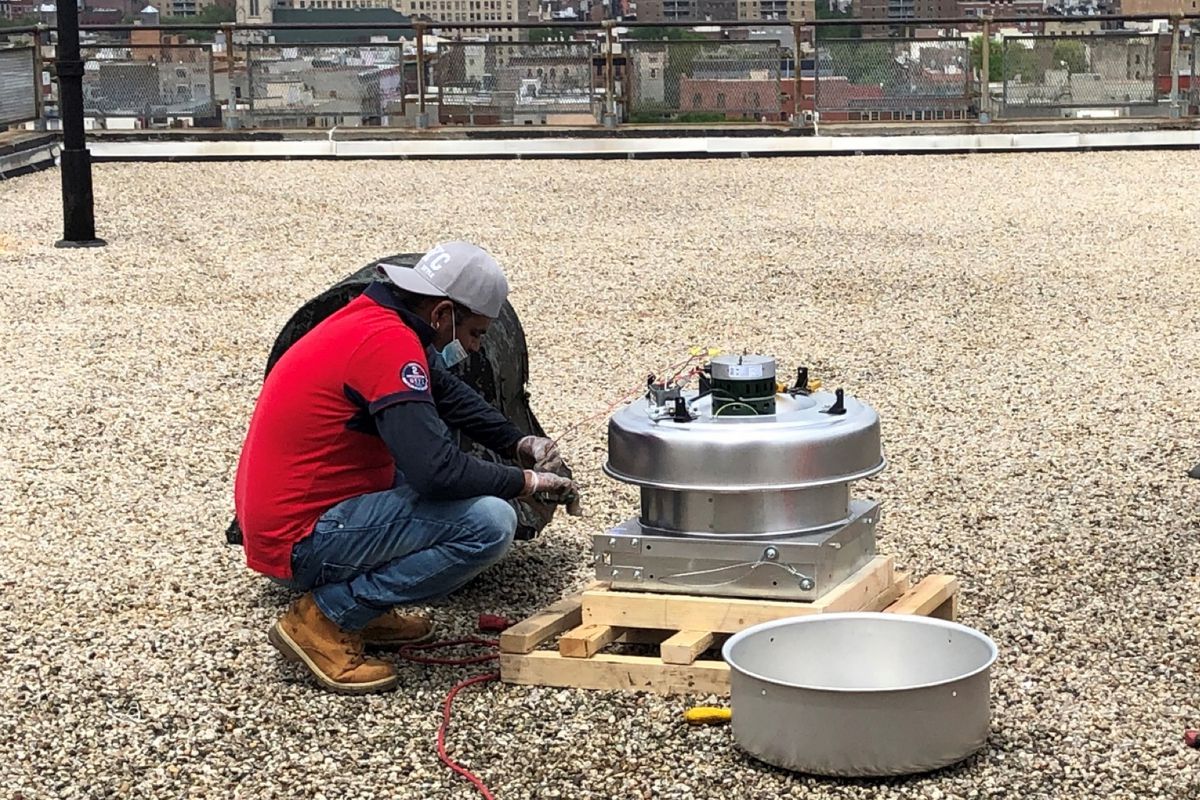 A worker installs a fan on the roof of a Wald Houses roof in the East Village.