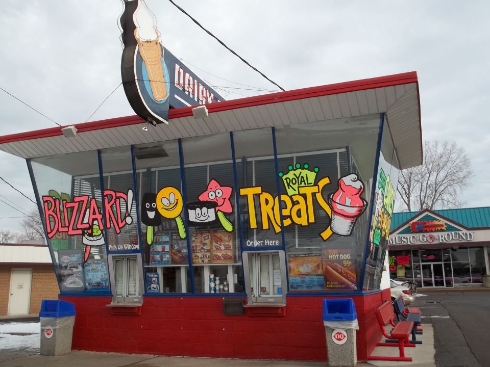 The exterior of an old-fashioned Dairy Queen with bright-painted decals on the windows. 