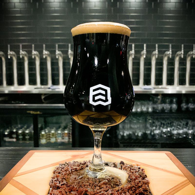 A bell-shaped glass filled with dark brown beer 