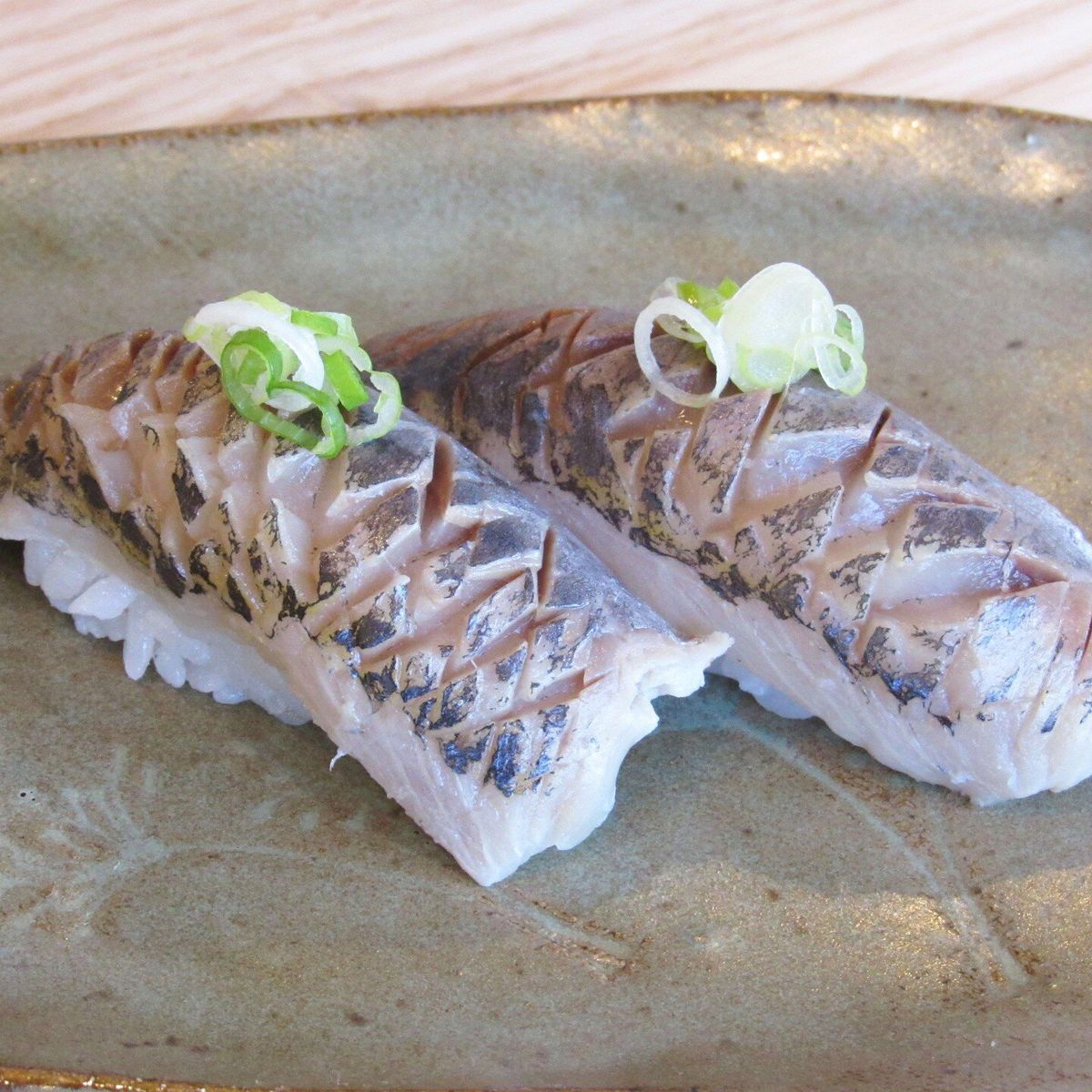 Skipjack nigiri that’s sliced along the top into diamonds and dressed with green onion. 