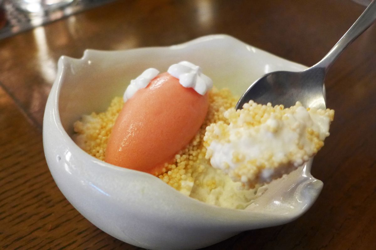 White rice pudding with orange sorbet on top.