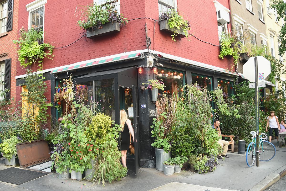 The exterior of the Spotted Pig, which is at a corner and is painted black, with lots of plants