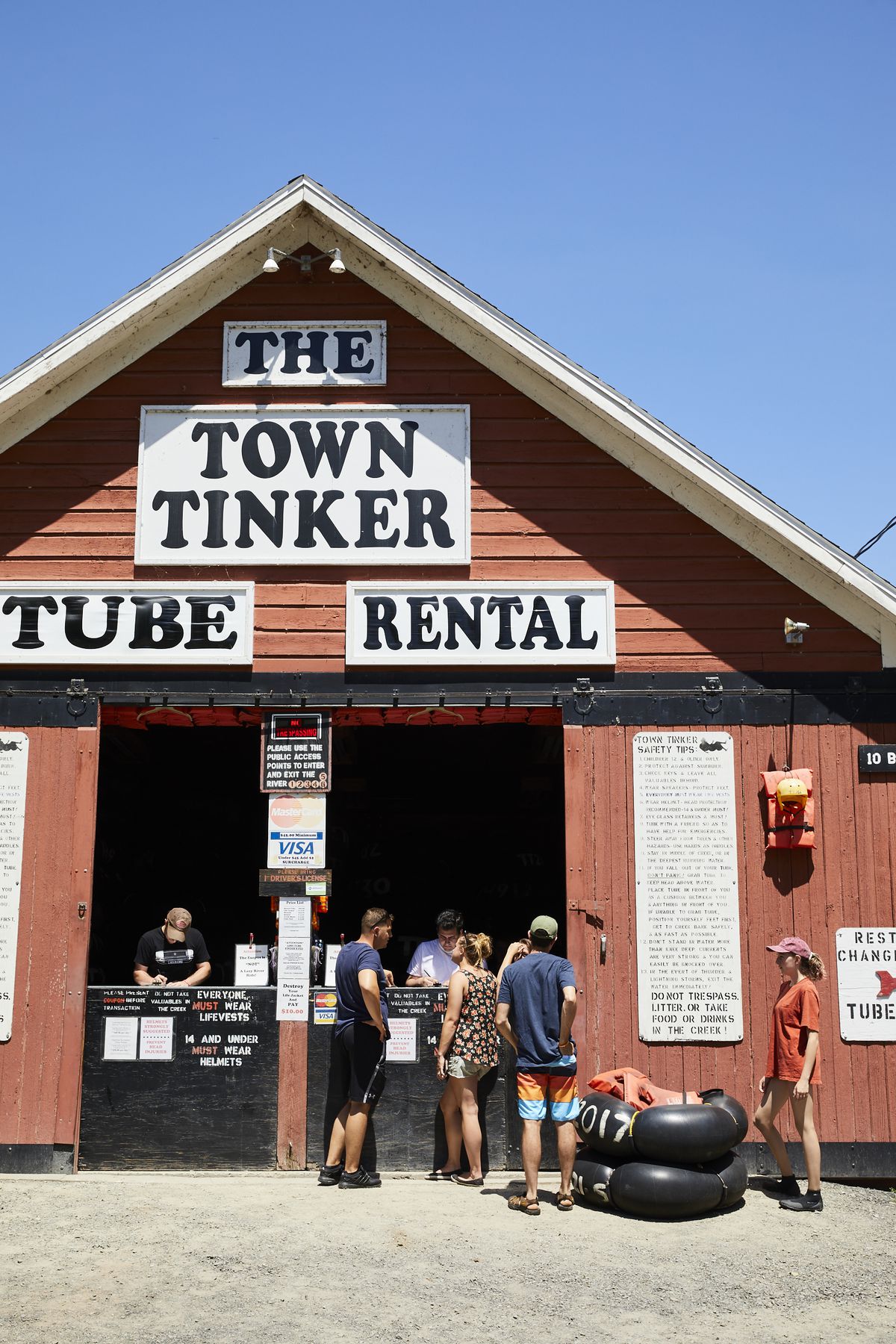A red shed with a sign that reads The Town Tinker Tube Rental. There are people standing outside and inside the shed.
