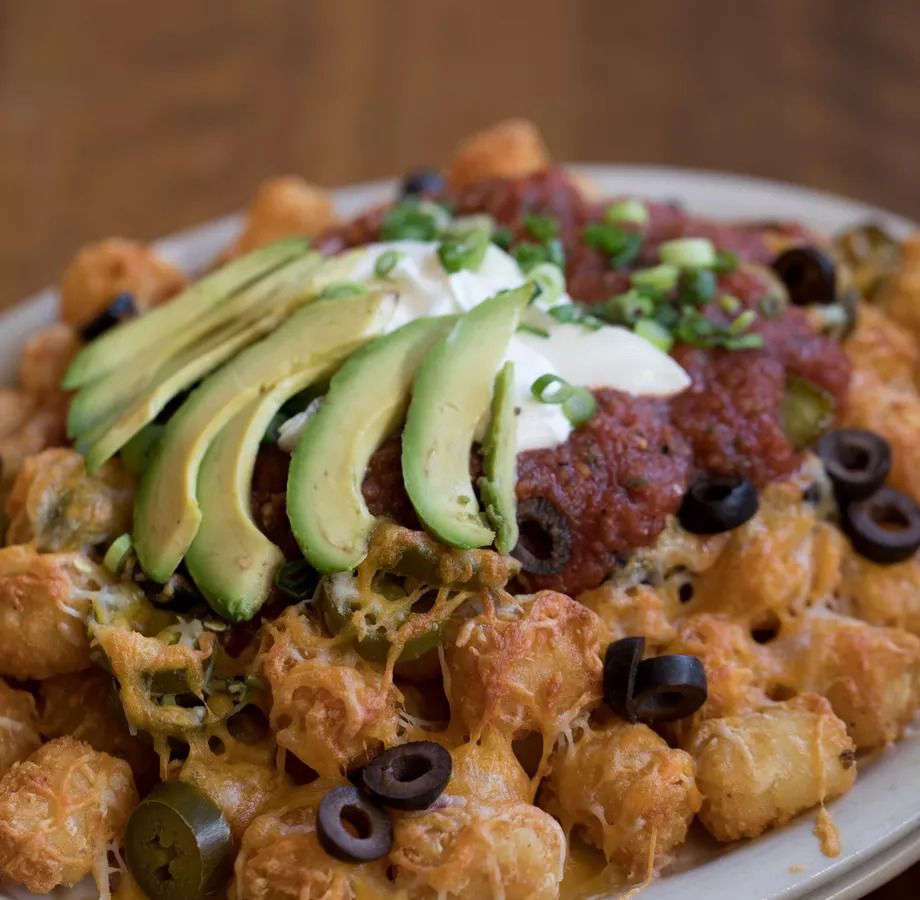 A picture of tater tots with avocado, sour cream, salsa, and olives at Oaks Bottom Public House.