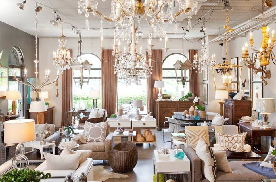 Big, light showroom with lots of white furniture and many chandeliers