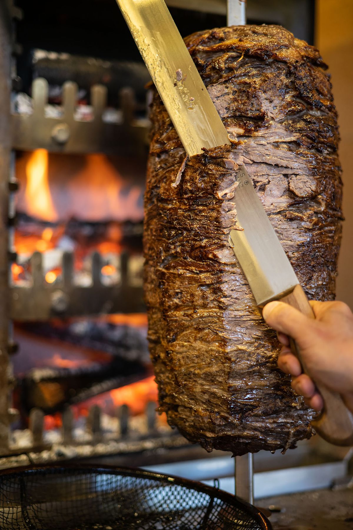 Shaving roasted meat from a vertical spit in a new restaurant.
