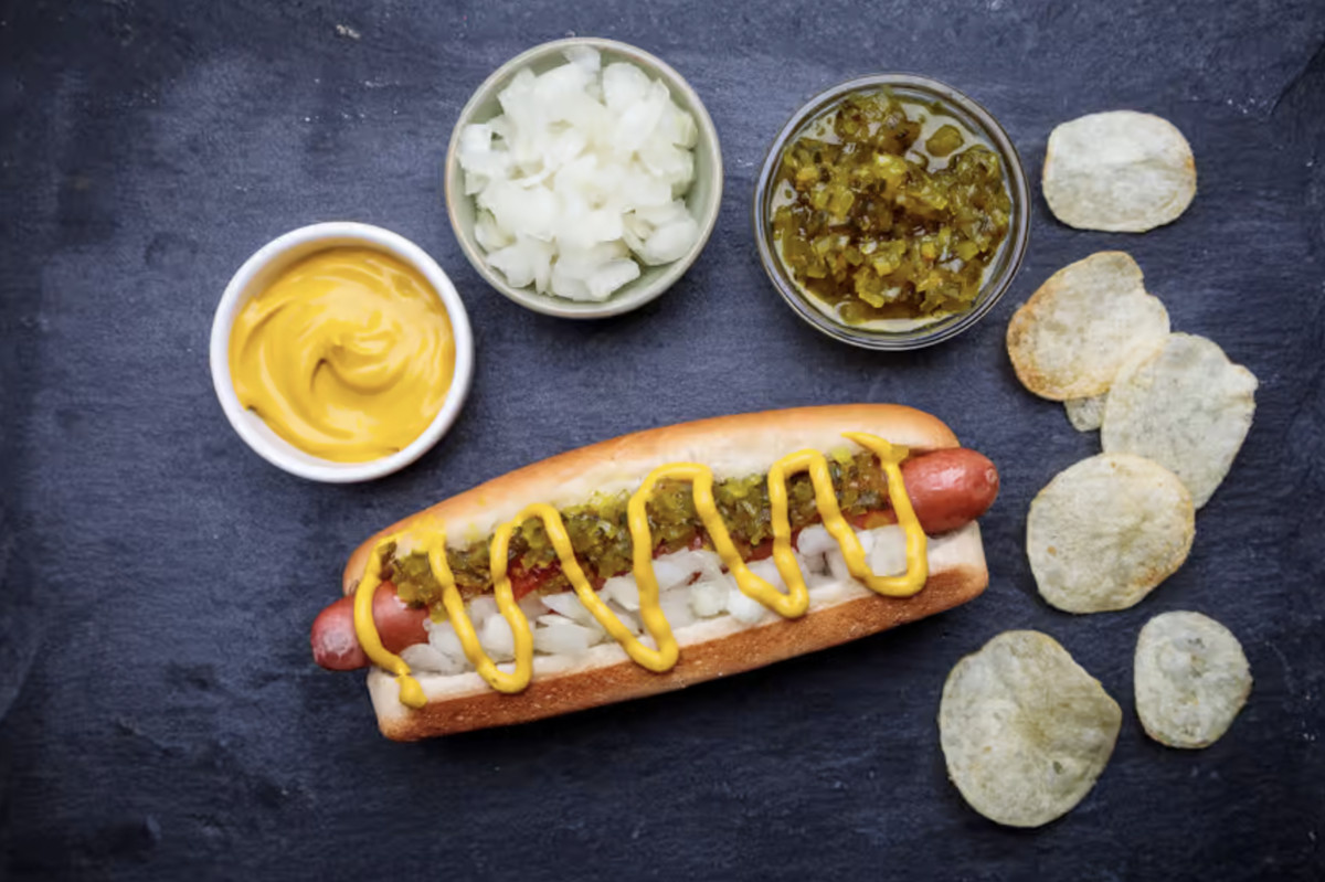 A hot dog topped with relish, chopped onions, and mustard.