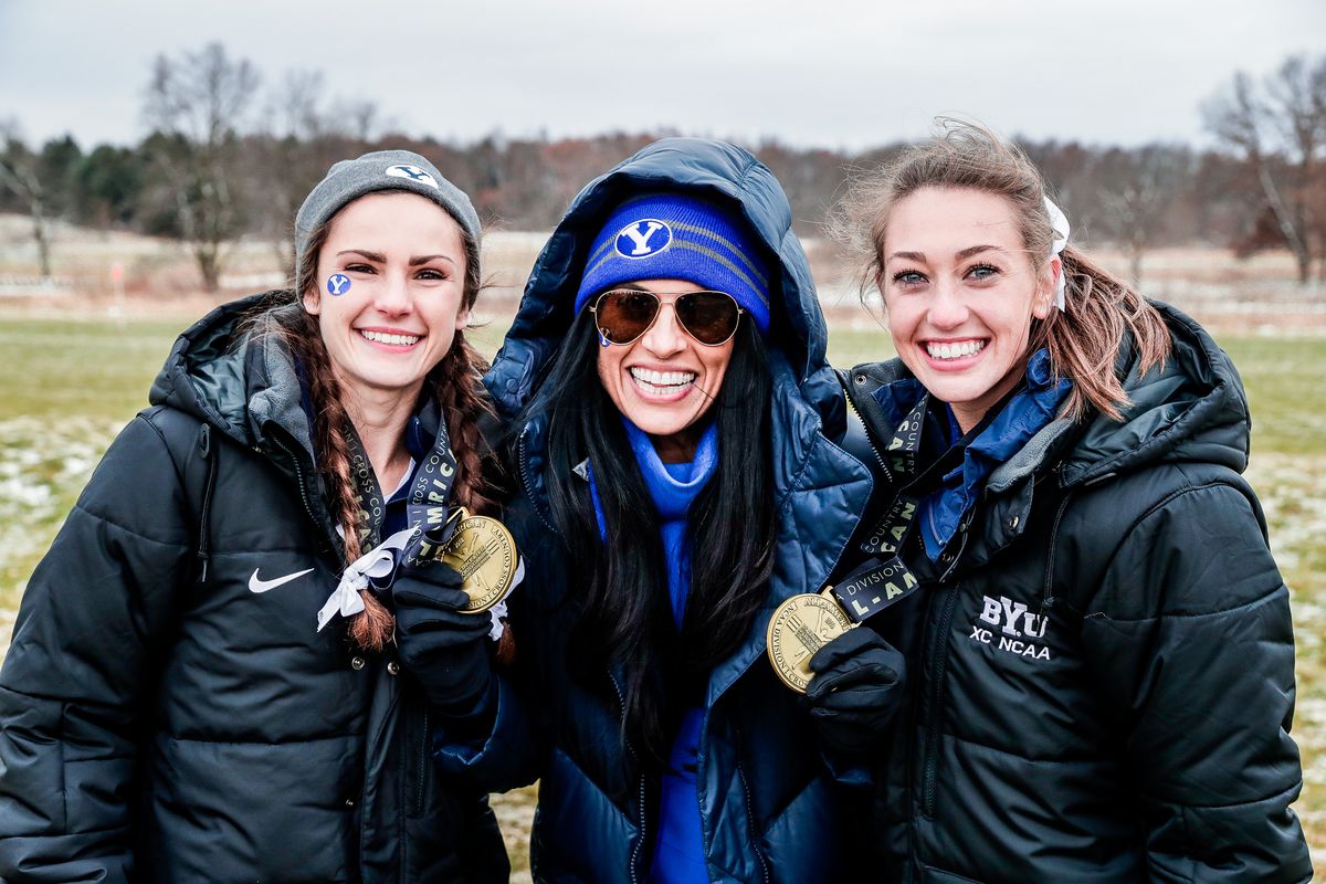 Erica Birk-Jarvis, left, and Courtney Wayment celebrate with coach Diljeet Taylor, center, after receiving All-America honors at the NCAA Championships.