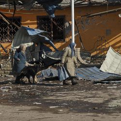 Elderly residents walk past damaged buildings in Debaltseve, Ukraine, Friday, Feb. 20, 2015. After weeks of relentless fighting, the embattled Ukrainian rail hub of Debaltseve fell Wednesday to Russia-backed separatists, who hoisted a flag in triumph over the town. The Ukrainian president confirmed that he had ordered troops to pull out and the rebels reported taking hundreds of soldiers captive.