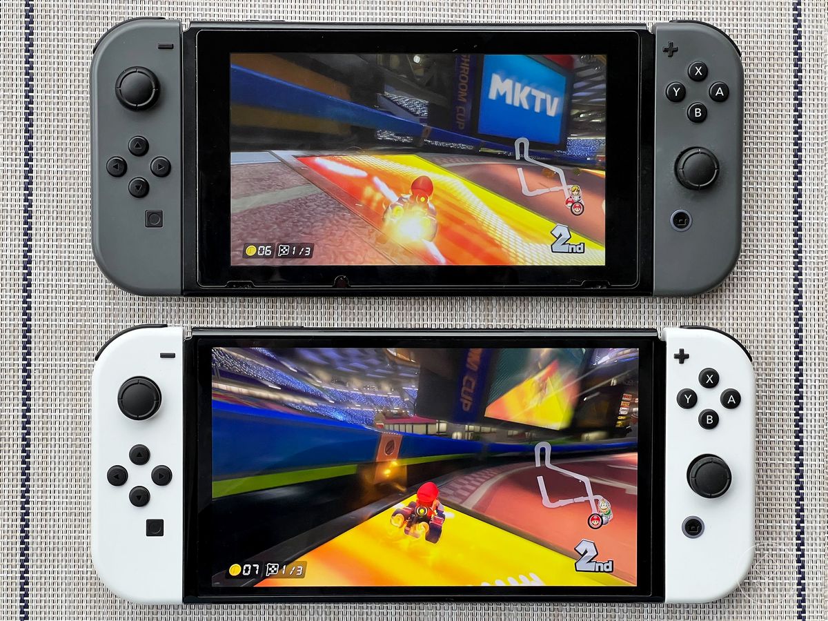 a photo of the original Switch (with dark gray Joy-Cons) above the OLED Switch (with white Joy-Cons), with Mario Kart 8 Deluxe running on both systems
